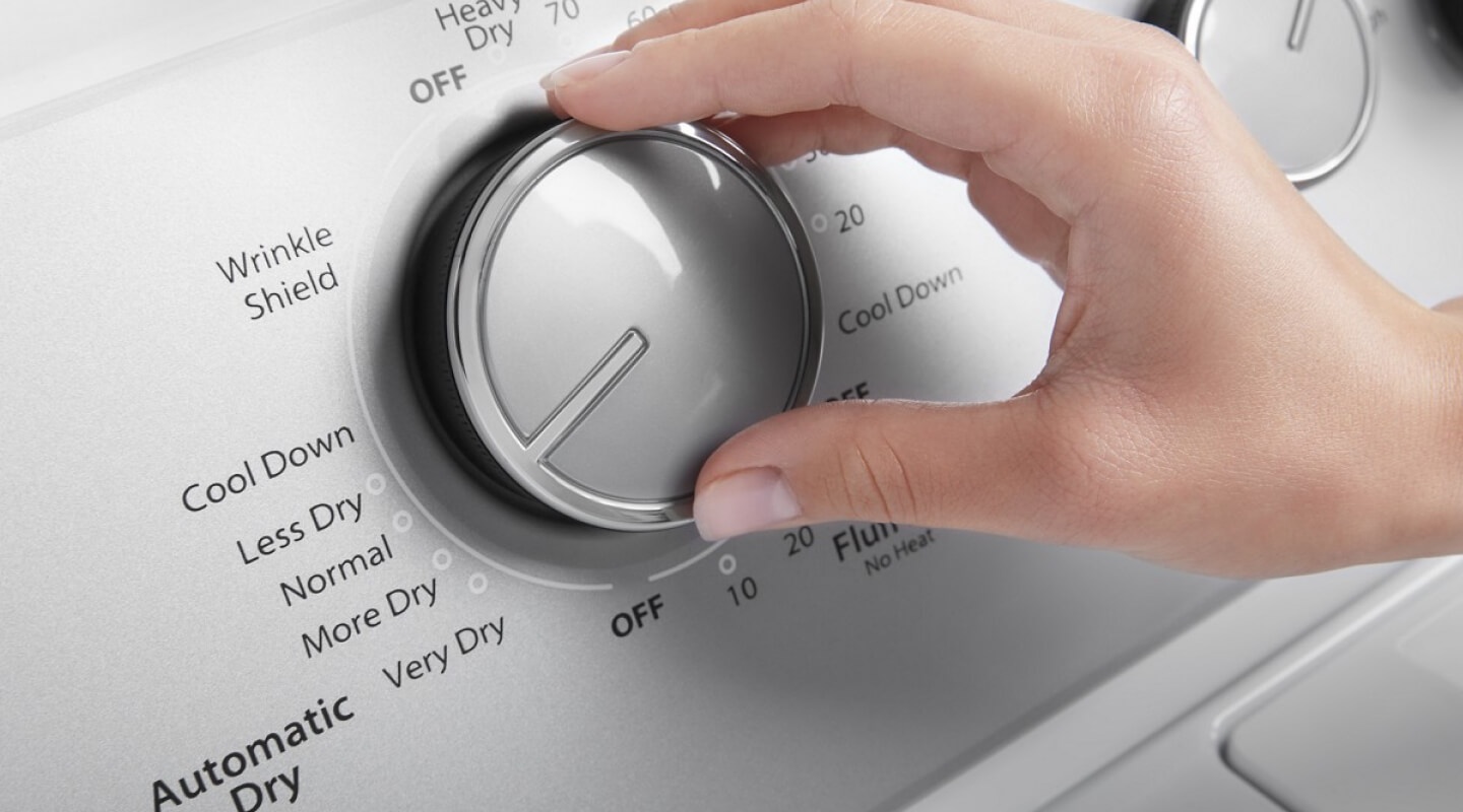 Hand turning a dryer control knob