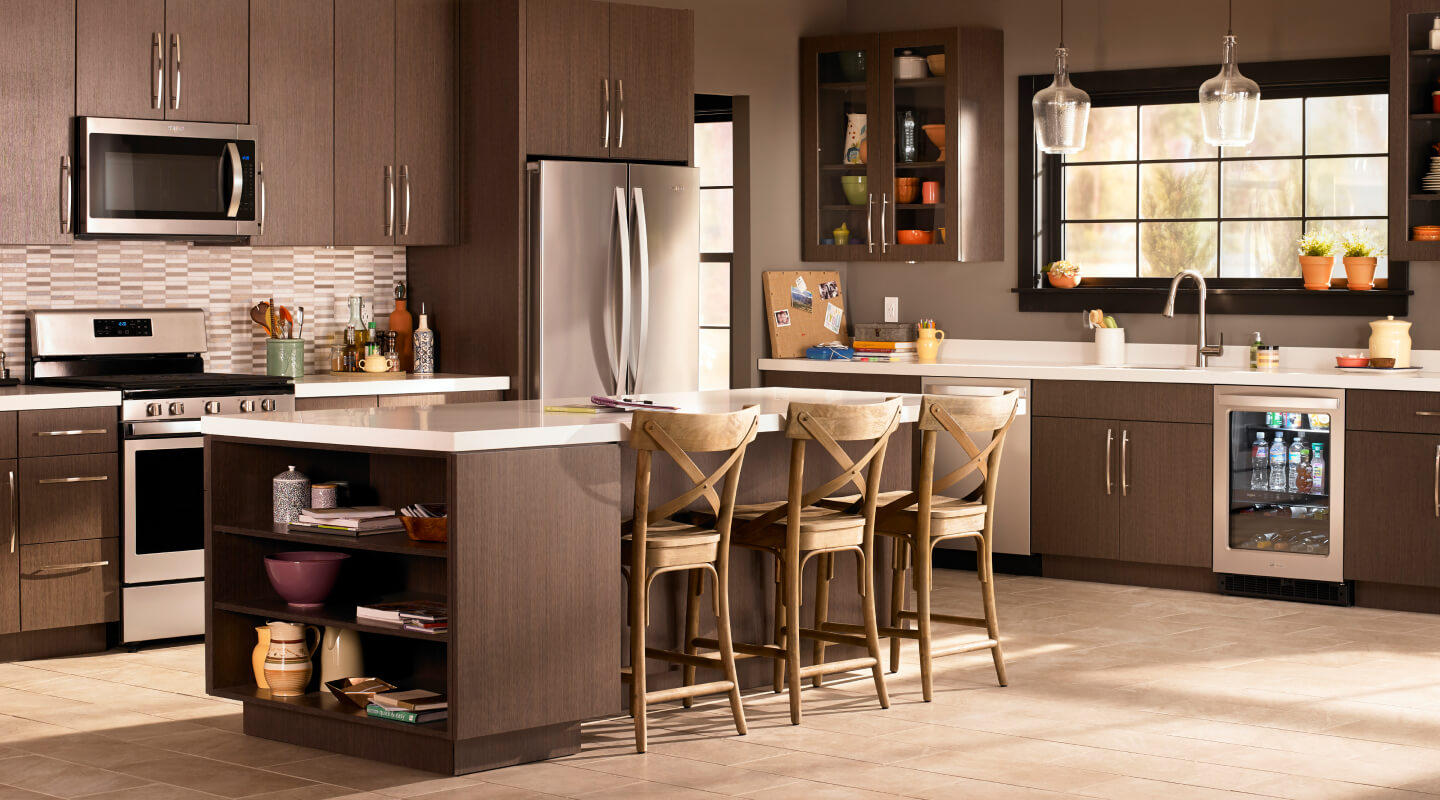 A kitchen with brown cabinets and stainless steel Whirlpool® appliances