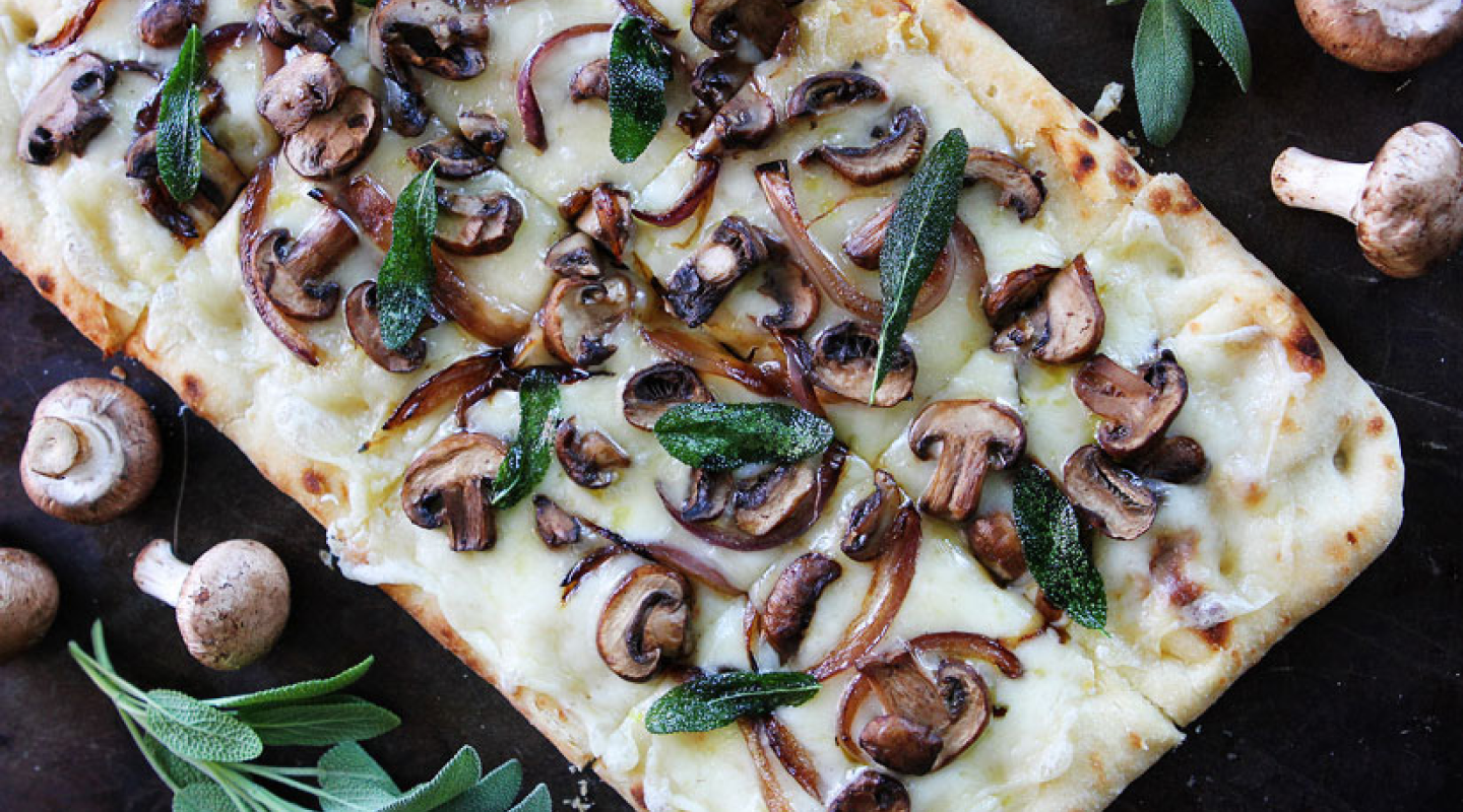 Flatbread pizza topped with cheese, mushrooms and herbs