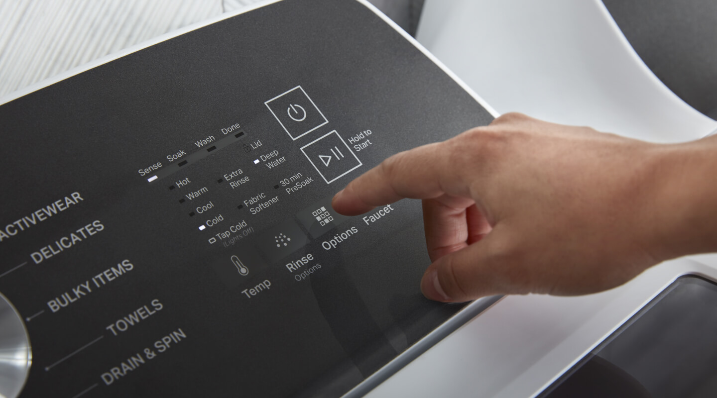 A person’s hand, operating the control panel of their washing machine