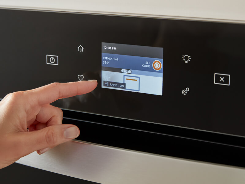 A person selecting a setting on an oven control panel