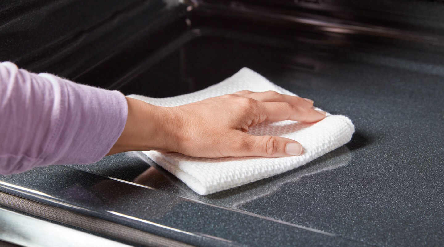 A person cleaning the inside of an oven