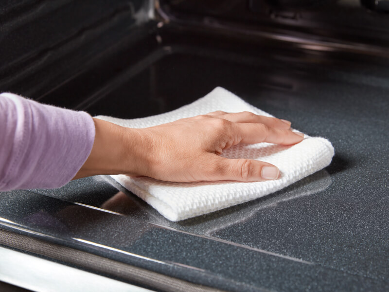 A person cleaning the inside of an oven