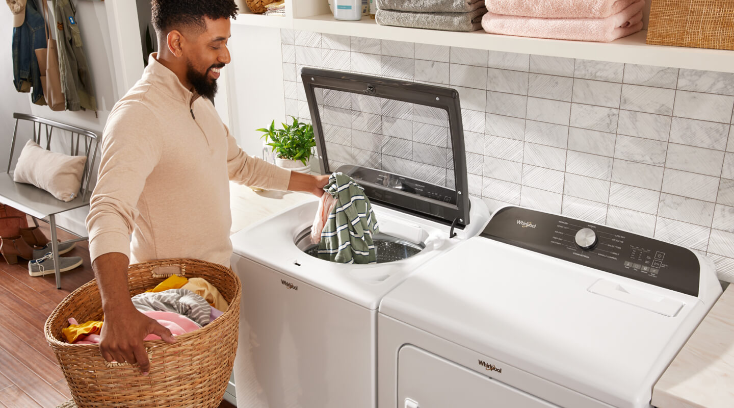 Person adding clothes into a top load Whirlpool® Washer