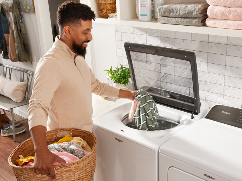 Person adding clothes into a top load Whirlpool® Washer