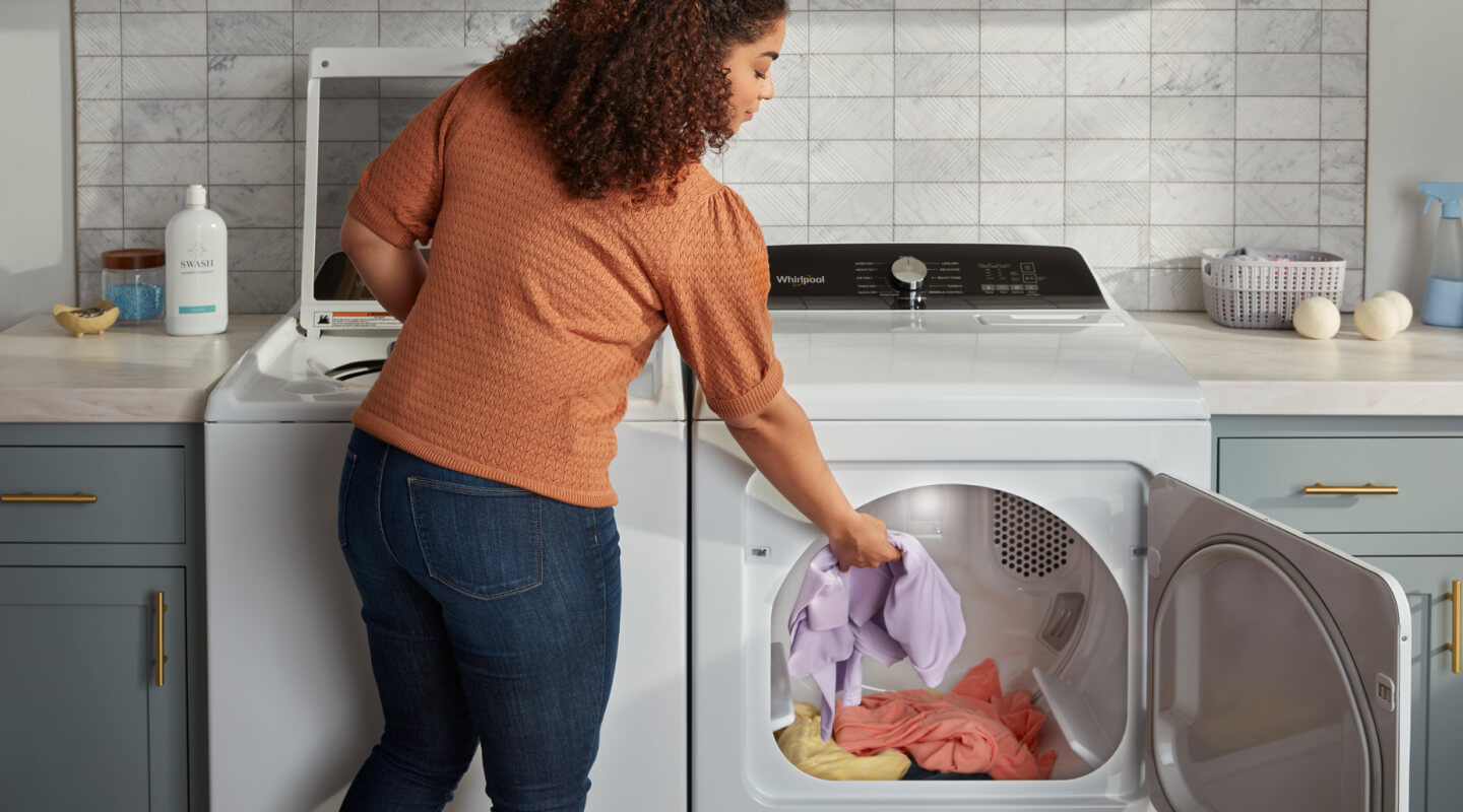 Person putting laundry into a dryer