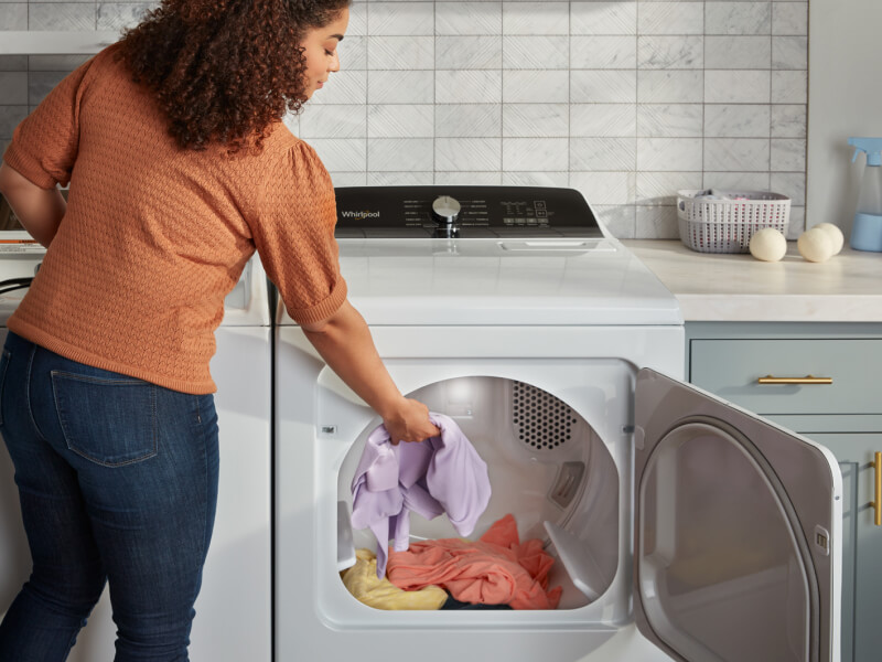 Person putting laundry into a dryer