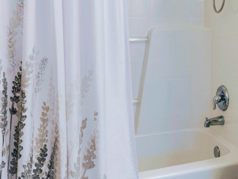 A hanging shower curtain with a design at the bottom. 