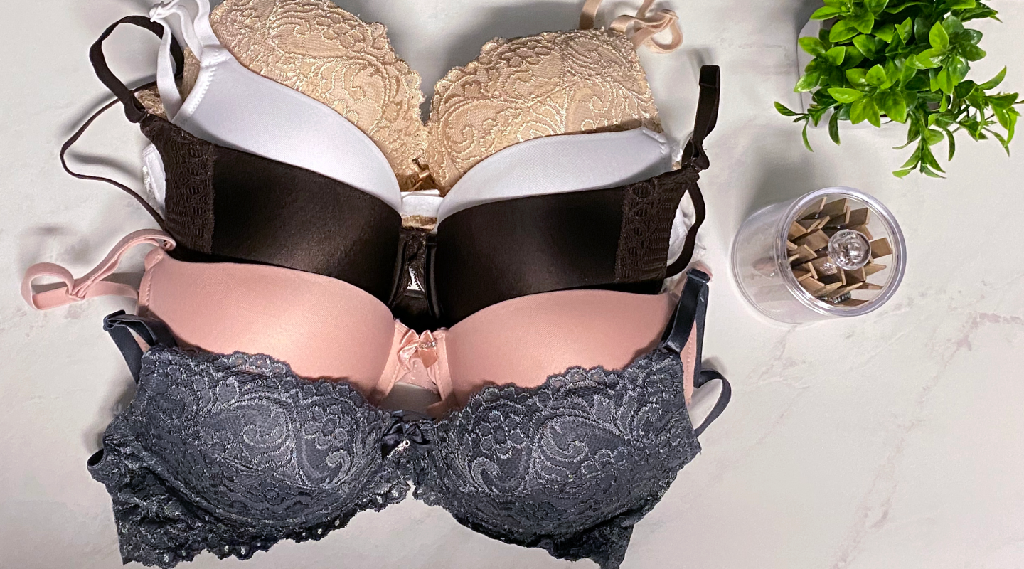 Variety of different colored bras next to clothespins and a plant