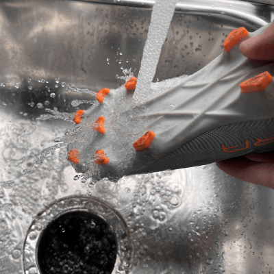 Rinsing the bottom of cleats under a faucet