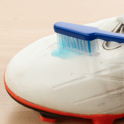 Toothbrush scrubbing a white cleat