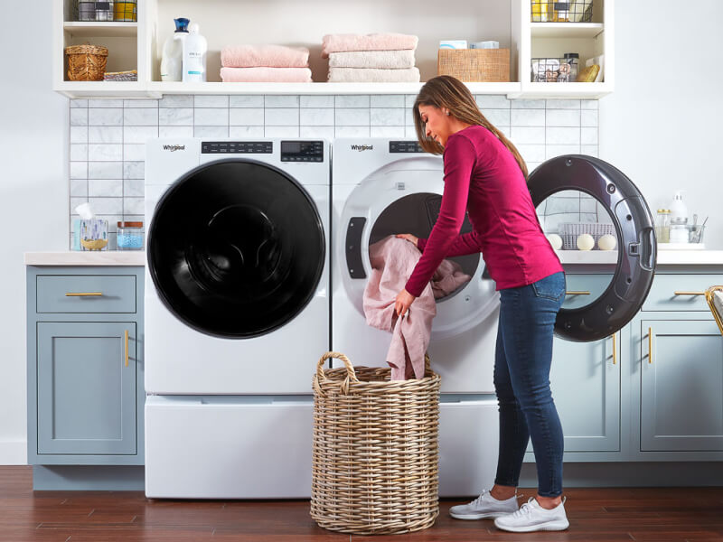 Person loading laundry in a front load dryer