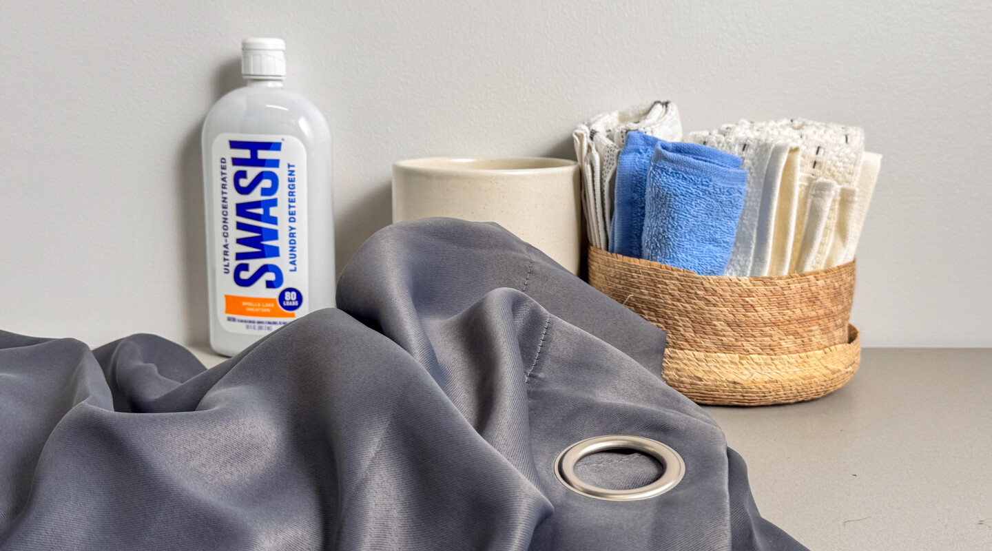 Grey curtains near a bottle of Swash® Laundry Detergent