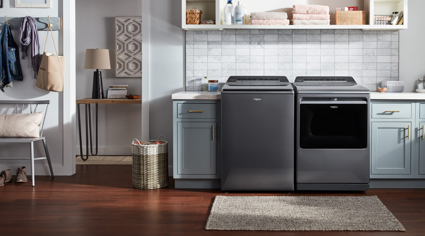 Laundry room with a grey top load washer and dryer set by Whirlpool brand