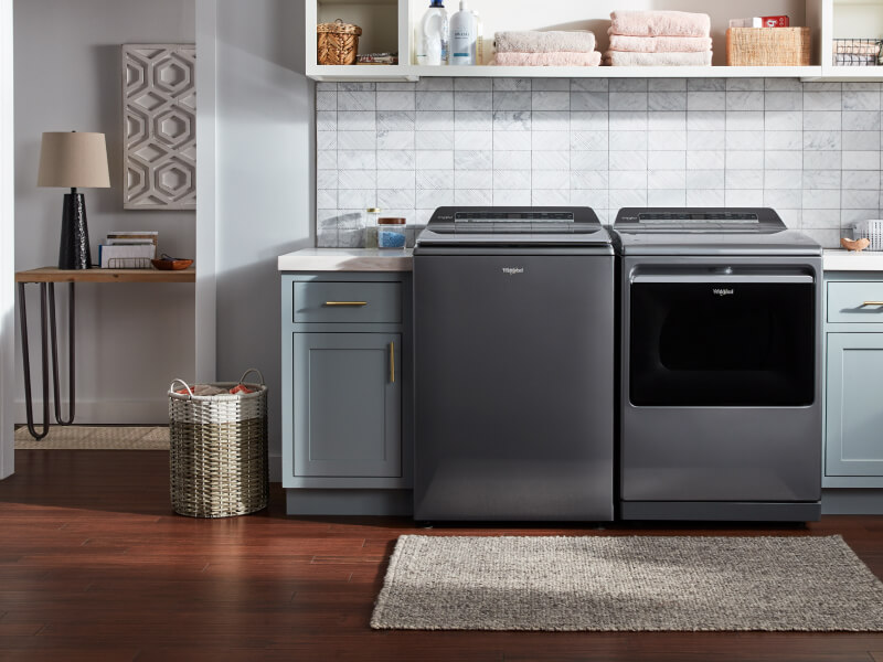 Laundry room with a grey top load washer and dryer set by Whirlpool brand