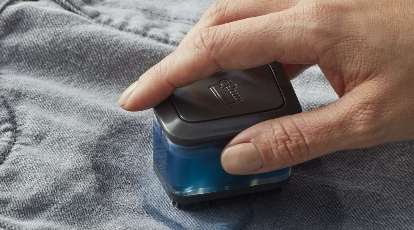 A closeup of a hand of a woman spot cleaning a garment. 