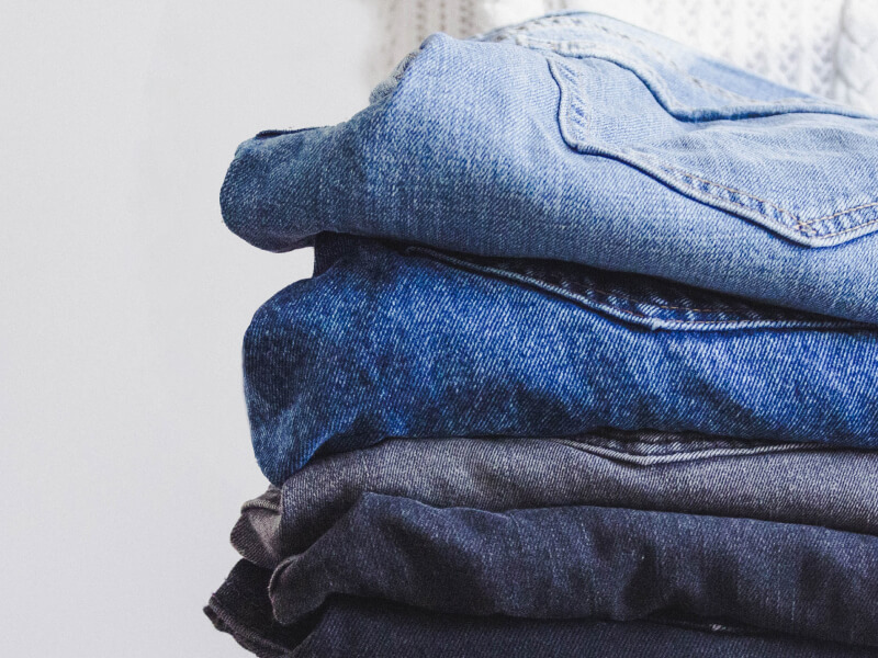 Four pairs of folded blue jeans