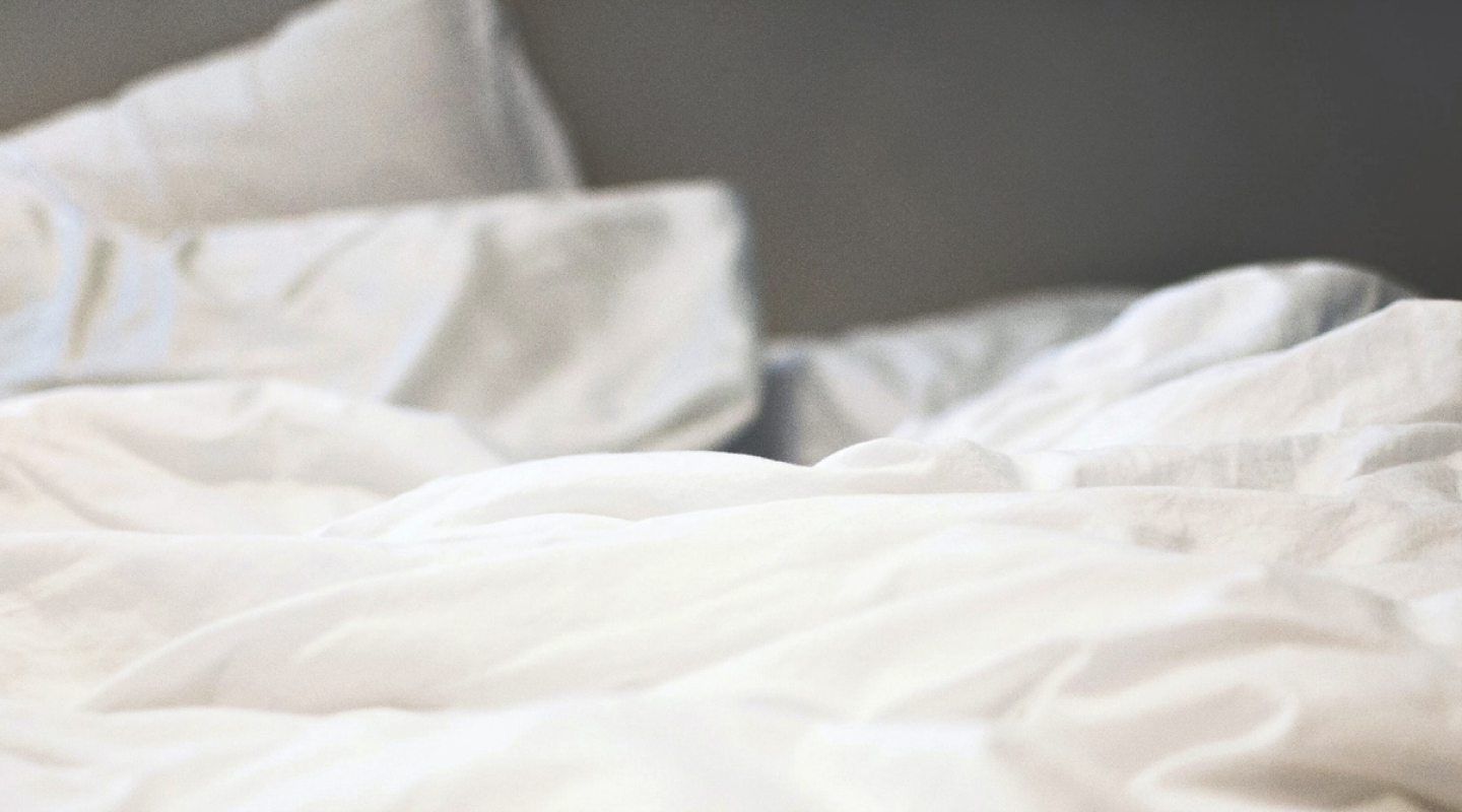 A cozy bed with white bed sheets