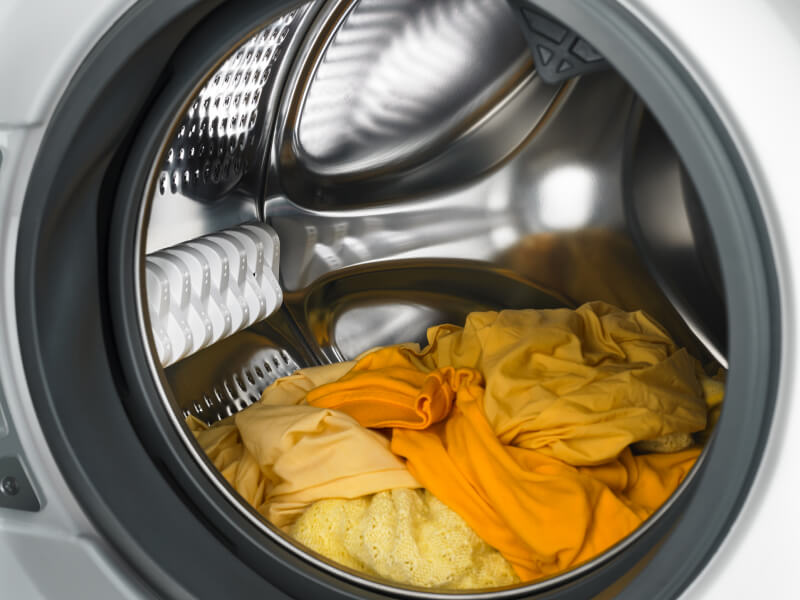 Yellow and orange laundry in a dryer.