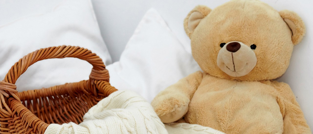 A stuffed animal next to a basket with a blanket