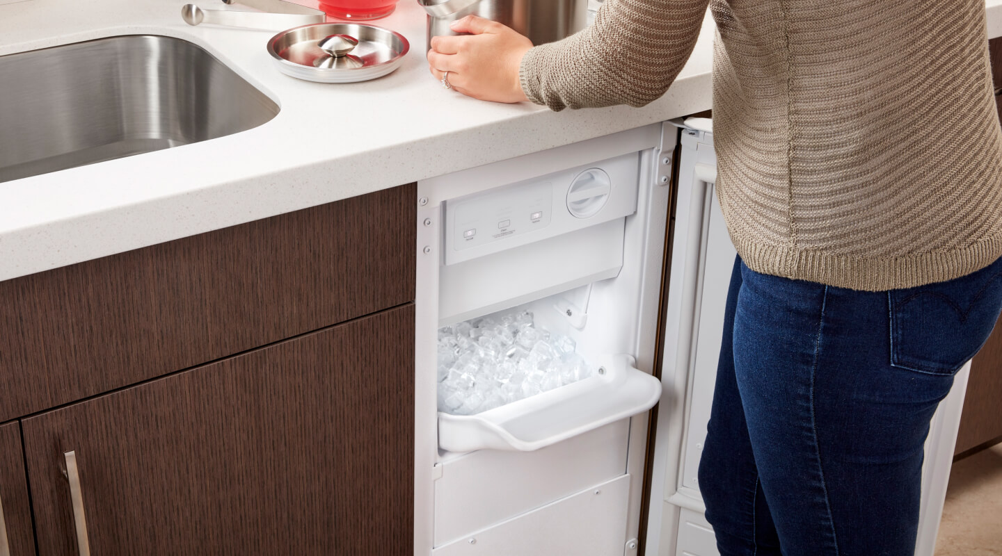 Person standing in front of an open undercounter ice maker