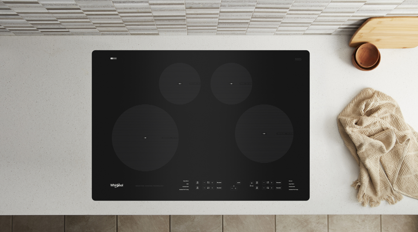 Whirlpool® Induction Cooktop in countertop next to towel and dishes