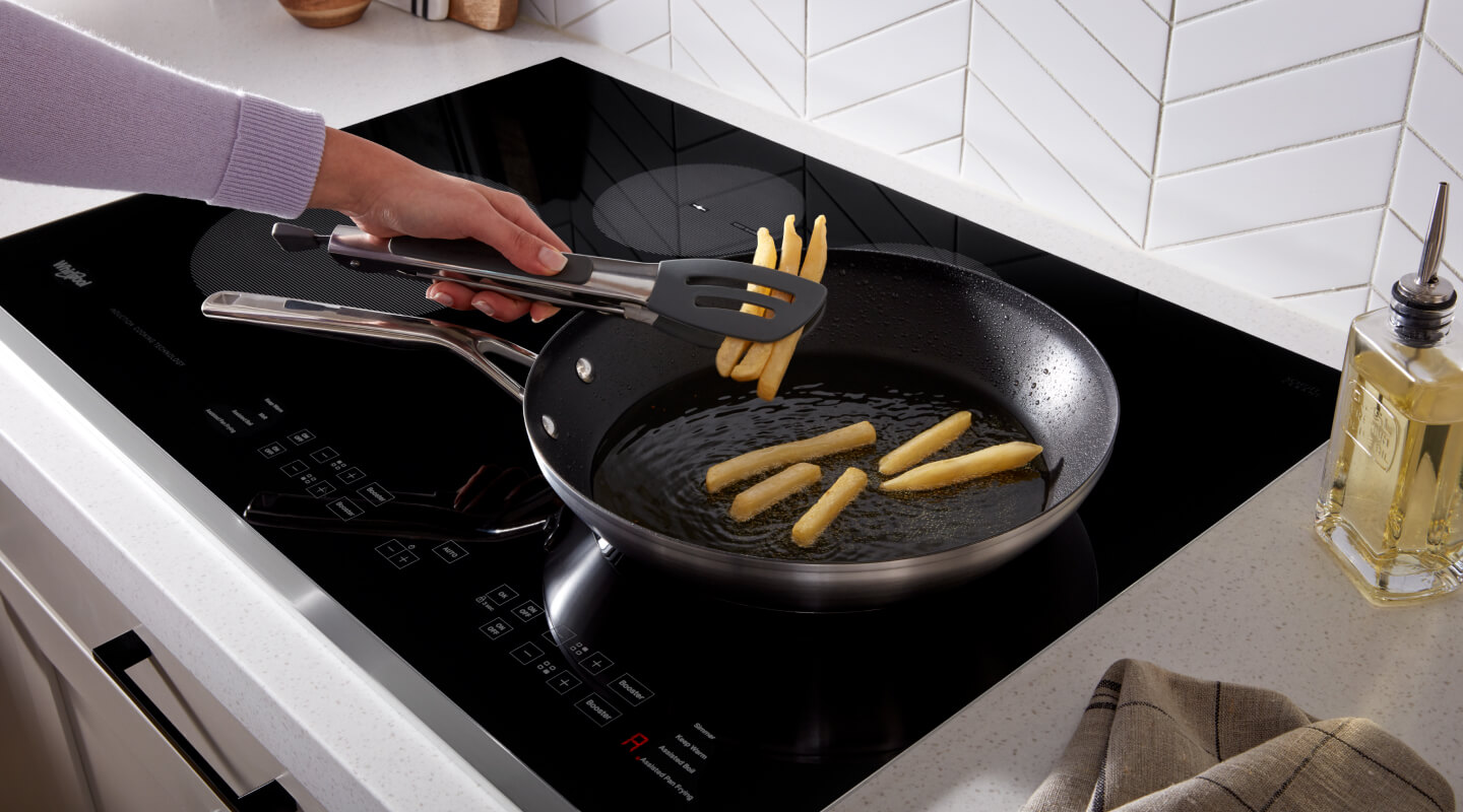 Person frying french fries in a frying pan on top of an induction cooktop
