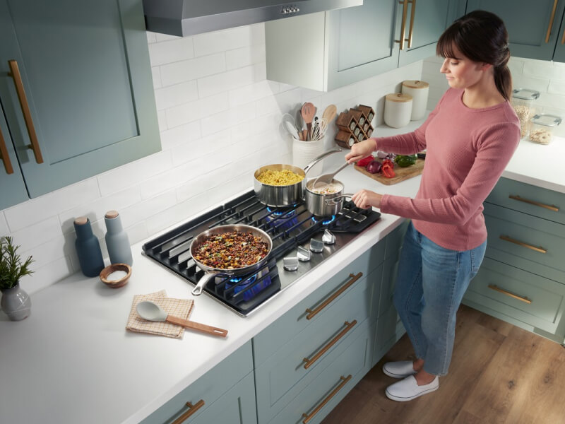 Person cooking a meal on a Whirlpool® Gas Cooktop
