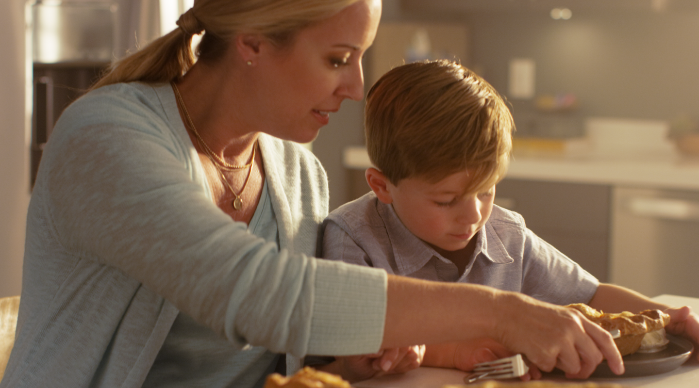 Adult and child serving pie at a kitchen island