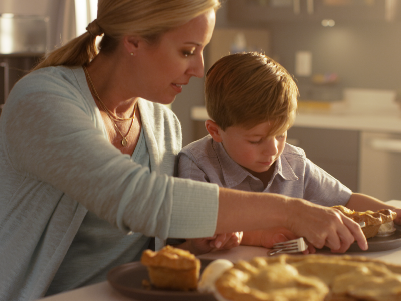 Adult and child serving pie at a kitchen island