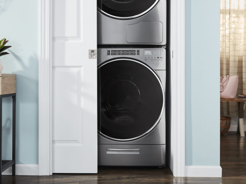 Stackable washer and dryer in a closet with door slightly ajar