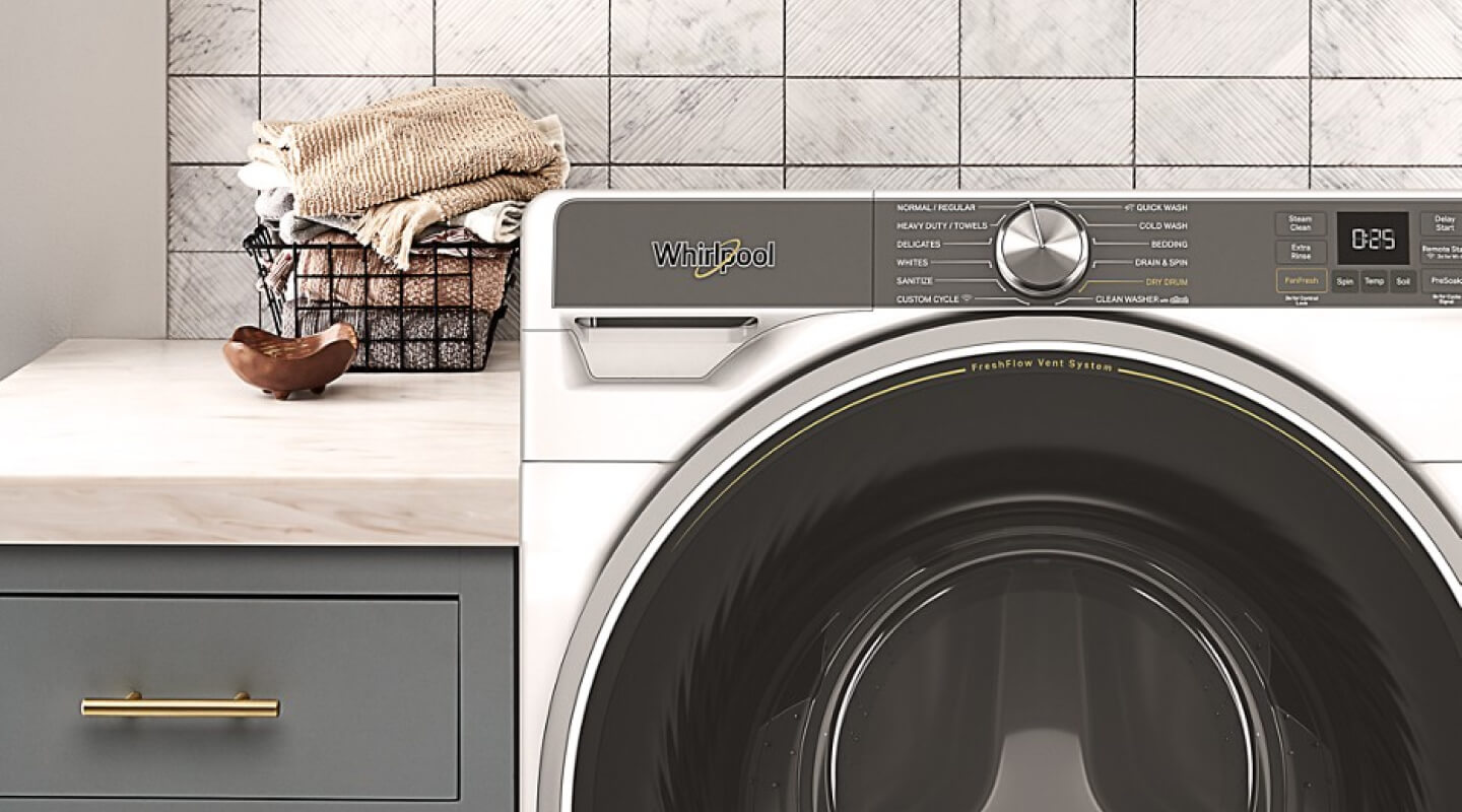 Close-up of Whirlpool® front load washer in front of gray tile backsplash