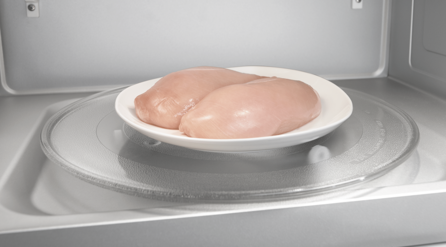 Two chicken breasts on a plate in a microwave
