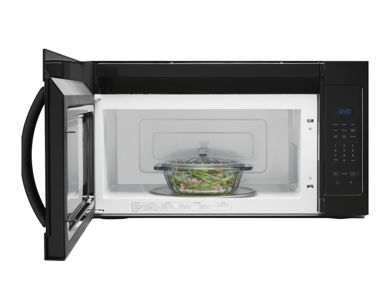 A glass container with meat and vegetables in a microwave