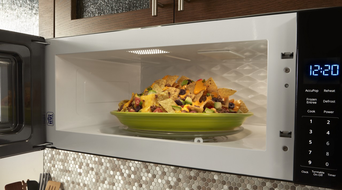 A green plate of nachos in a microwave