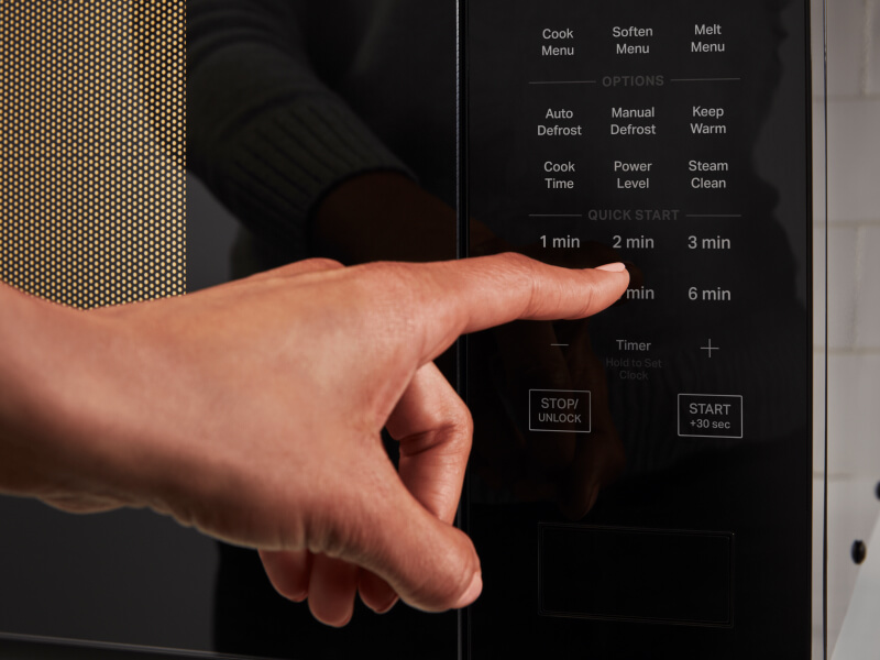 Person selecting a setting on a microwave control panel