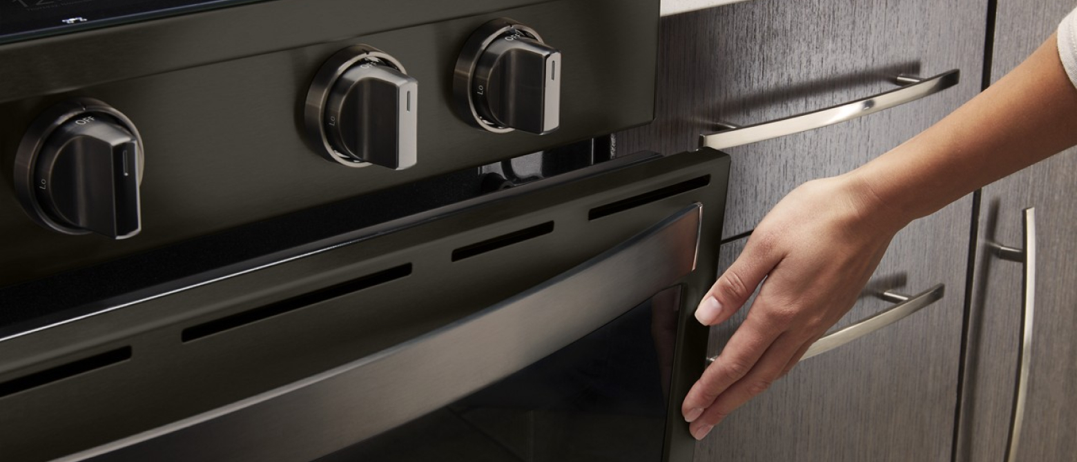A hand closing an oven door.