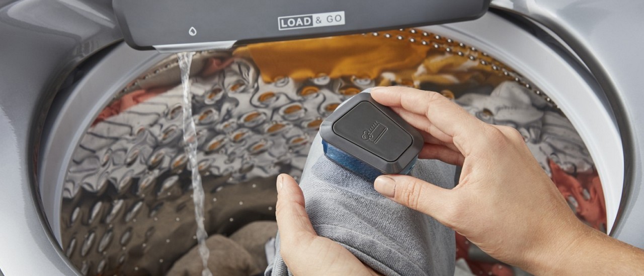 A person using a scrub brush filled with detergent on a stained piece of clothing