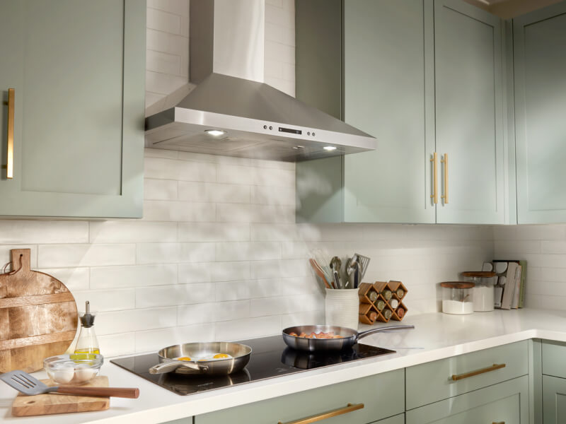Steam from two pans rising underneath a canopy range hood