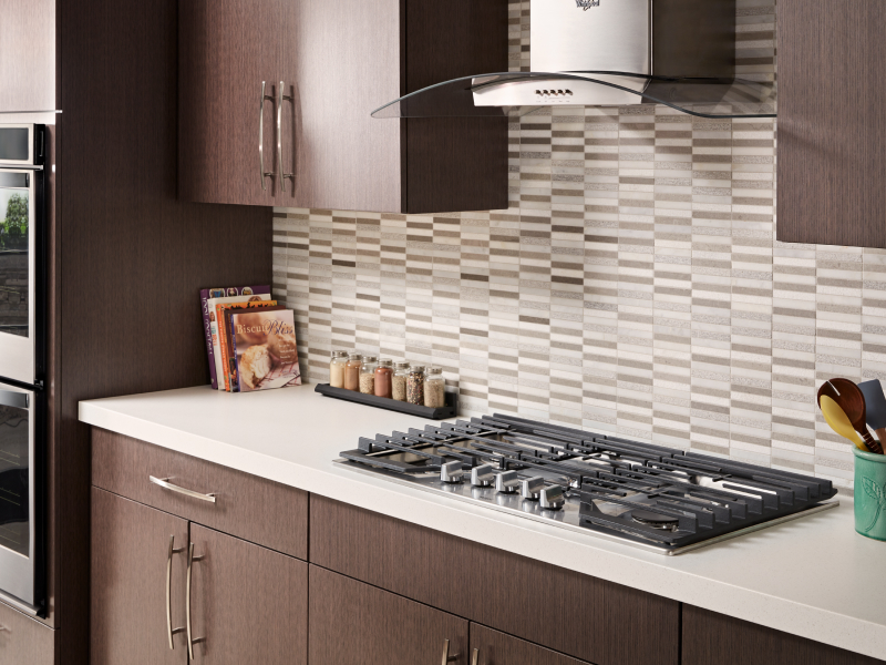 Gas cooktop installed into countertops with a vent hood above it