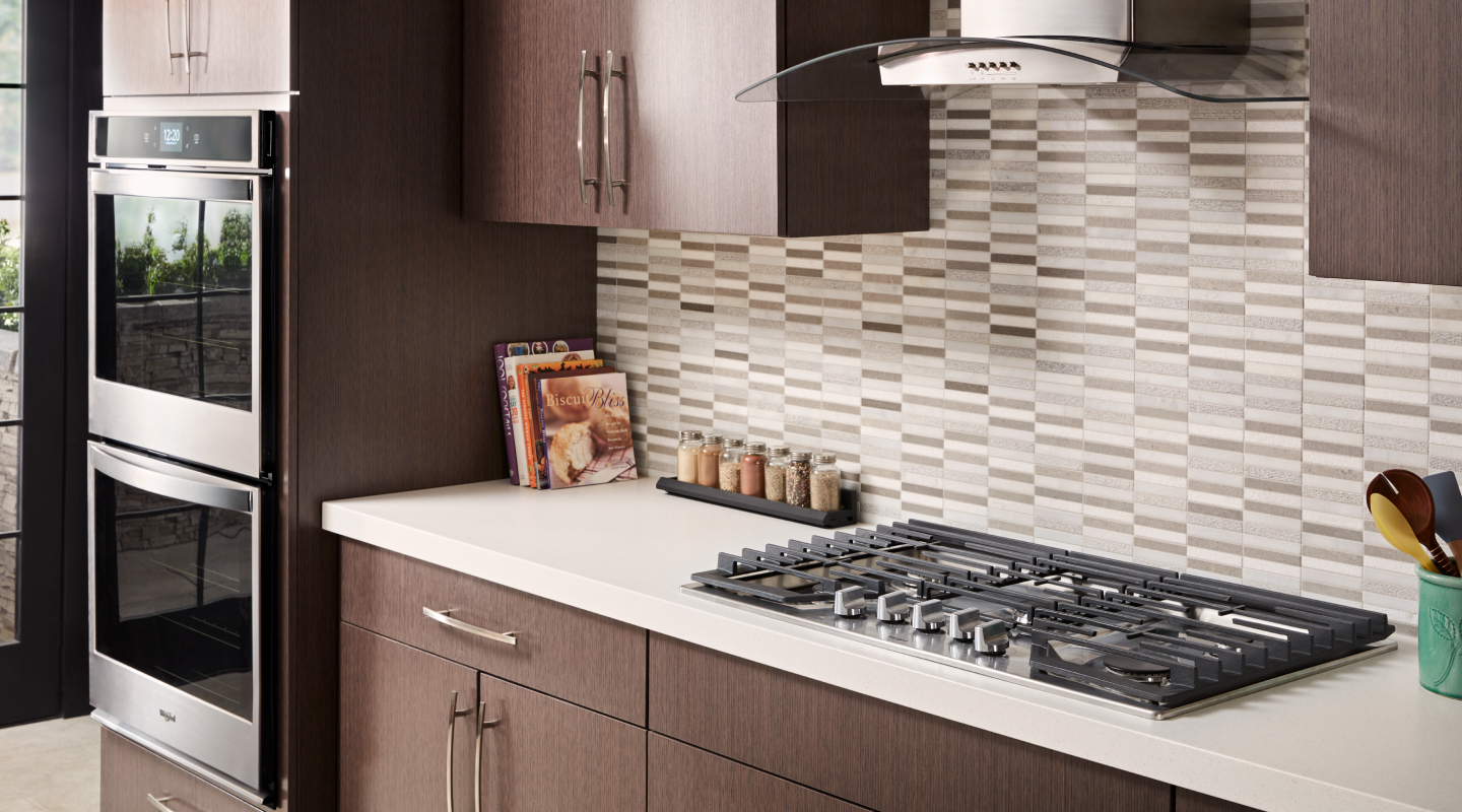 Gas cooktop installed into countertops with a vent hood above it