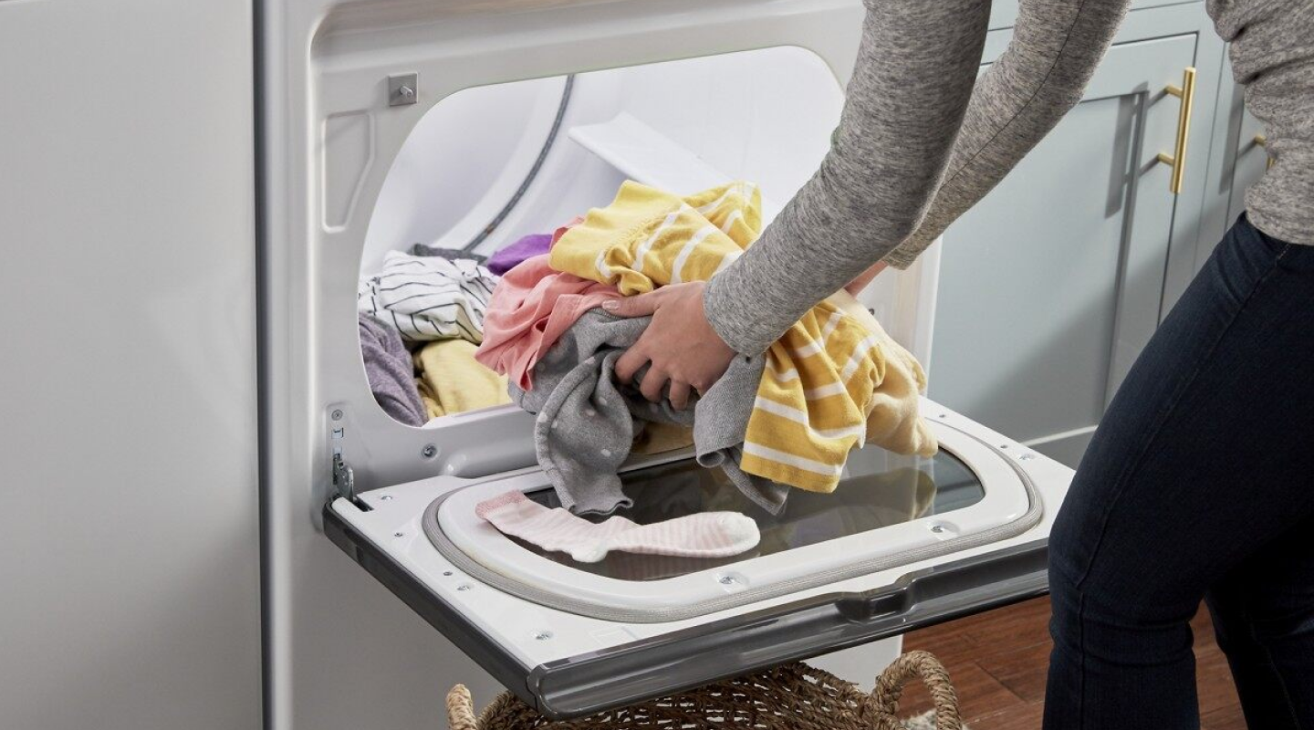 Person loading laundry into a dryer