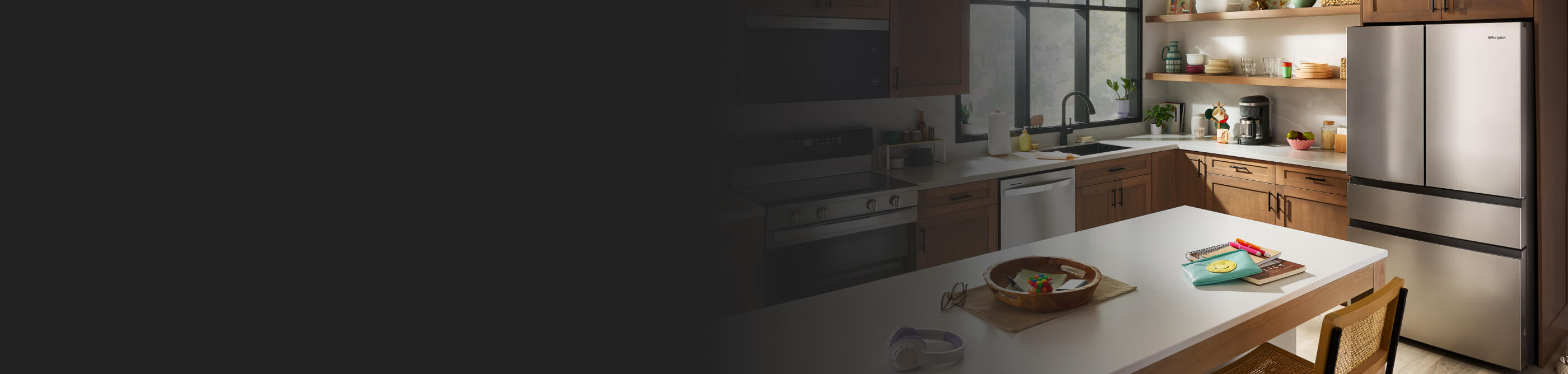  Pulled back view of a kitchen with stainless steel appliances including a refrigerator