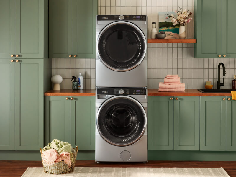 Stacked front load washer and dryer surrounded by green cabinets
