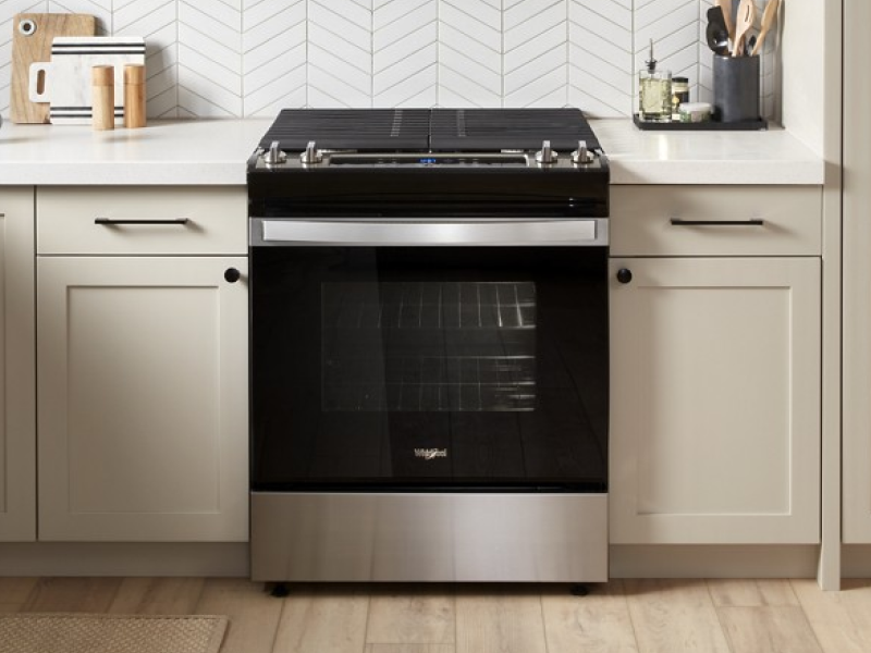 A black slide-in range in a rustic kitchen