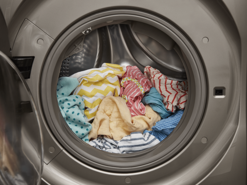 An open front load washer with a load of laundry inside