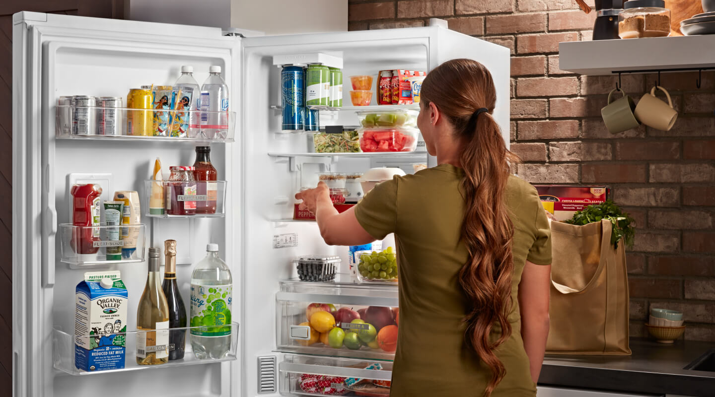 A person standing in front of their open fridge