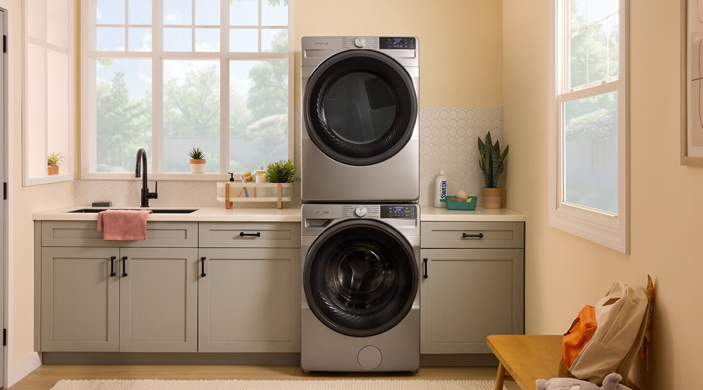 Stainless steel front load washer and dryer in a laundry room with gray cabinetry