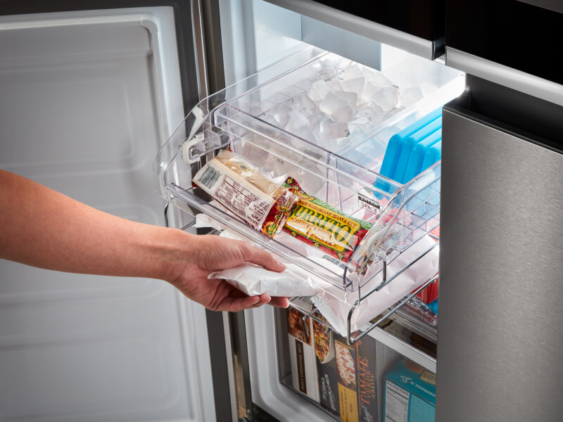 A person taking a popsicle out of a bottom freezer refrigerator