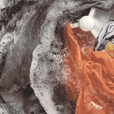 Interior of a Whirlpool® Washer with an impeller washing orange, gray and white garments